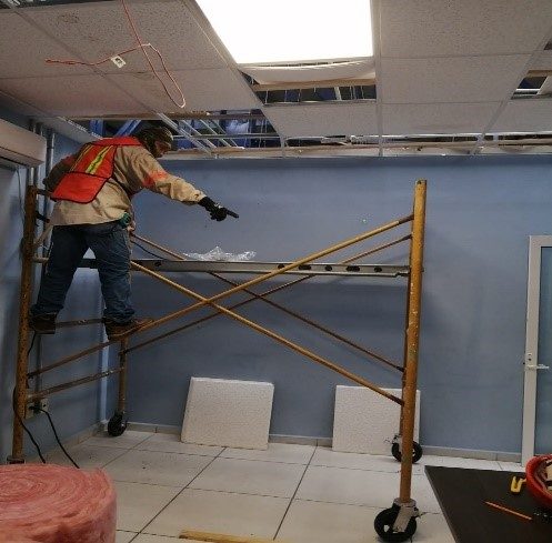 Trabajador JALMOR en andamio instalando aislamiento acústico en muro de nave industrial Altamira